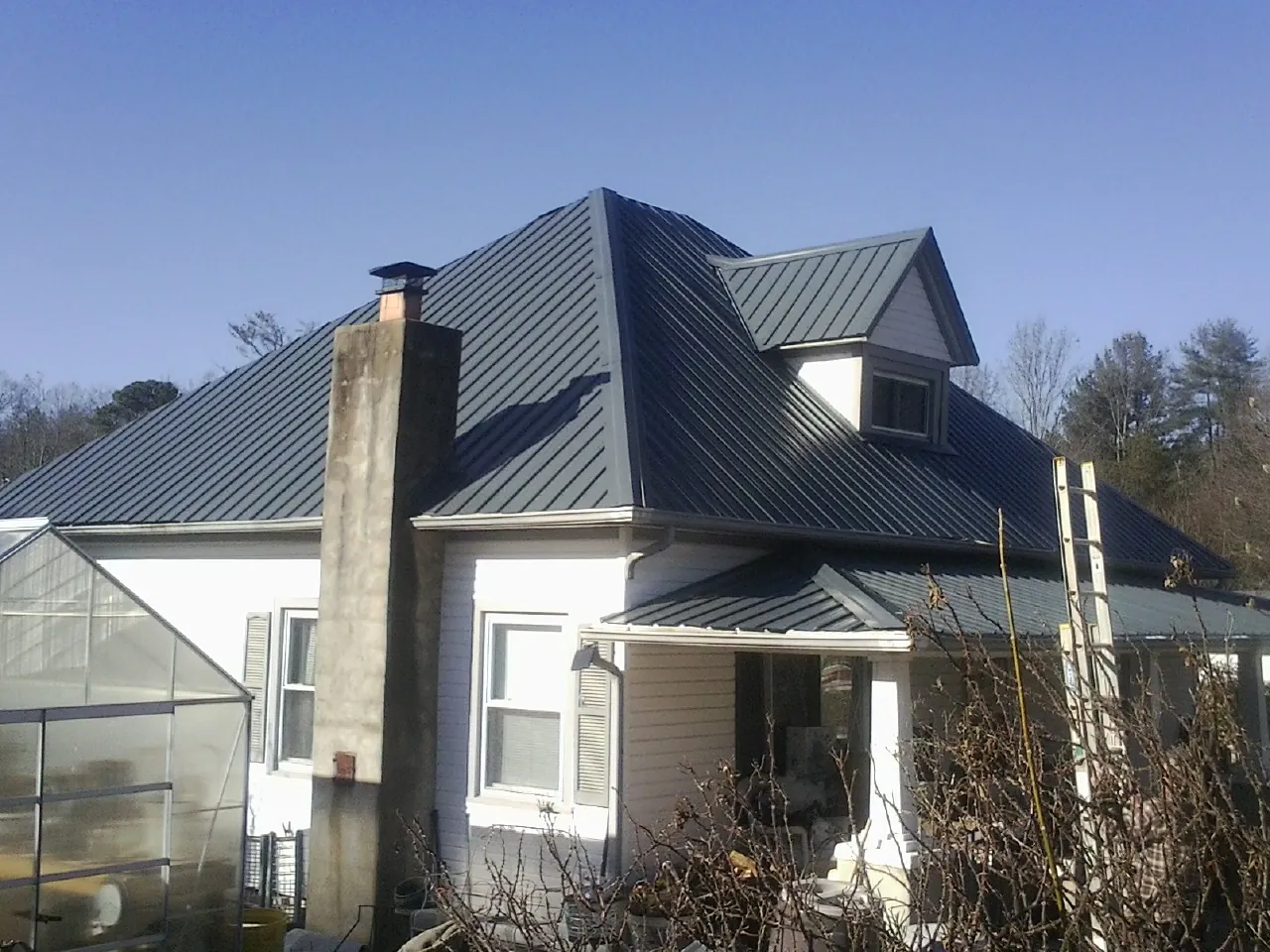 Dark blue standing seam metal roof on a white farmhouse with dormer — Slate & Tile Roof Repair by Roofing Brothers in Euclid