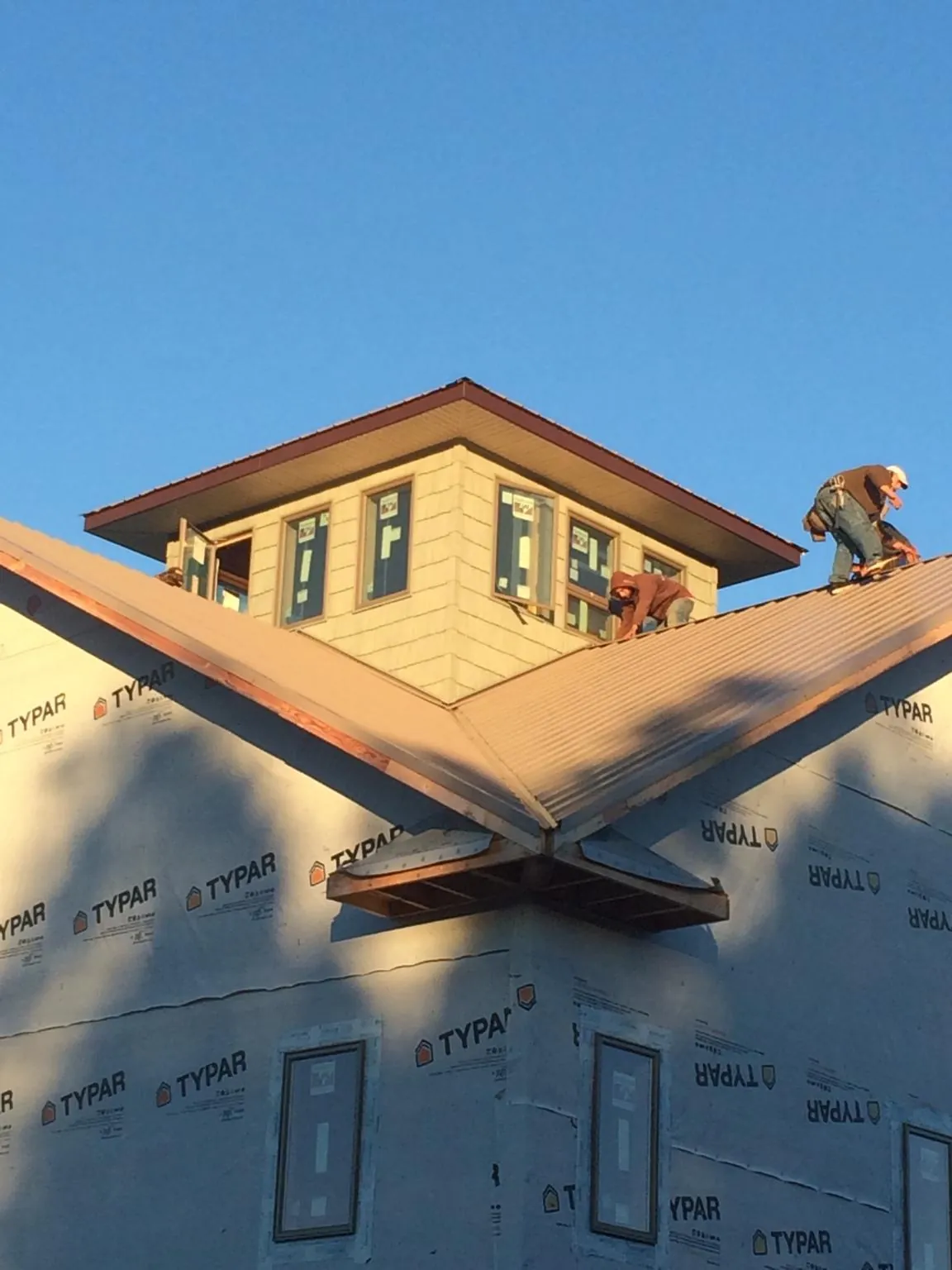 Roofers working around a rooftop cupola on a new metal roof at sunset — Roof Waterproofing in Euclid by Roofing Brothers